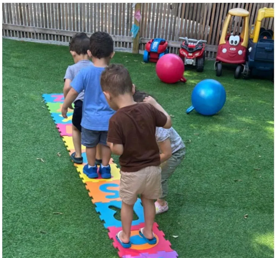 Crianças brincando no playground gramado e cercado do Kids Club